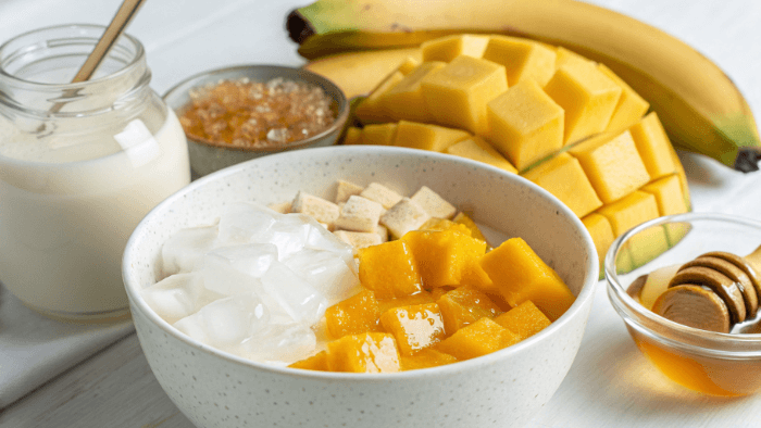 Mango, yogurt, milk, honey and ice ingredients displayed for mango smoothie