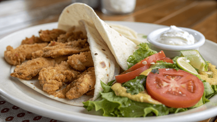 Preparing crispy chicken in a pan before assembling the wrap