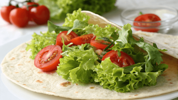 Rolling and assembling the tortilla wrap with chicken and veggies