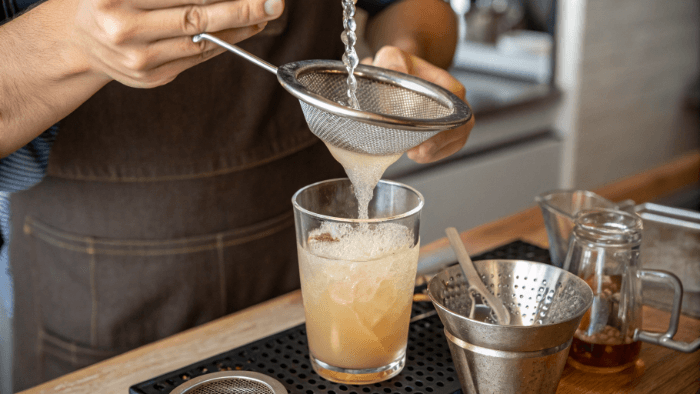 Straining and mixing lemon ginger detox drink