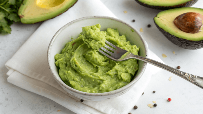 Spreading mashed avocado over crispy toast